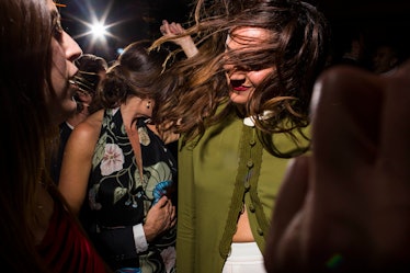 A woman in a green button-up sweater dancing in a crowd at W's Golden Globes party 