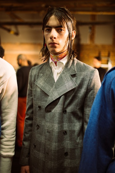 A young man posing in a grey plaid blazer