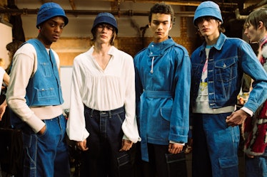 Four models posing for a photo, three in denim blue outfits and one in a white shirt 