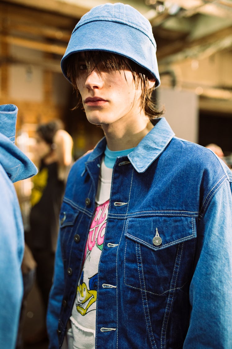 A male model wearing a denim bucket hat and a denim jacket 