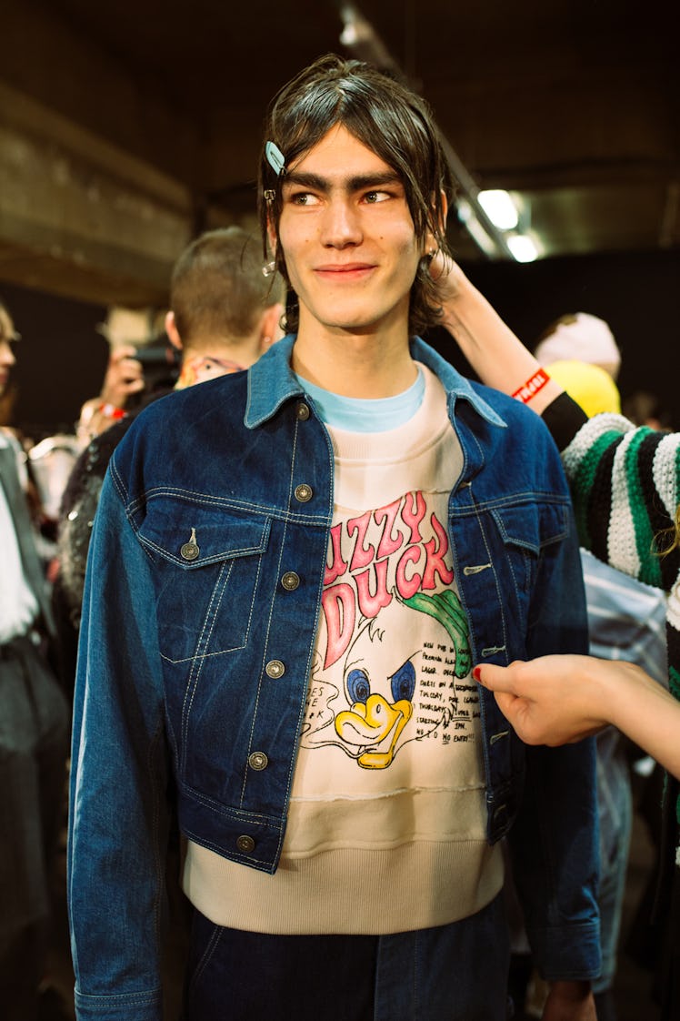 A model standing while wearing a denim Texas jacket and a white shirt