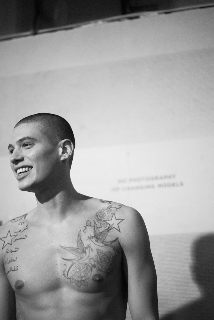 A shirtless tattooed male model on the runway at London Fashion Week