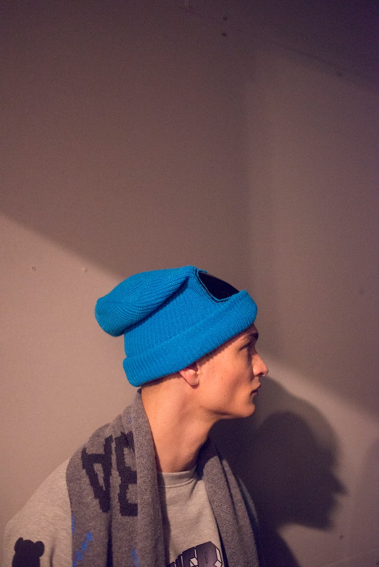 A model wearing a blue beanie backstage at London Fashion Week