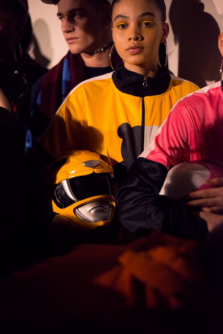 A model holding a yellow Power Ranger helmet backstage at London Fashion Week