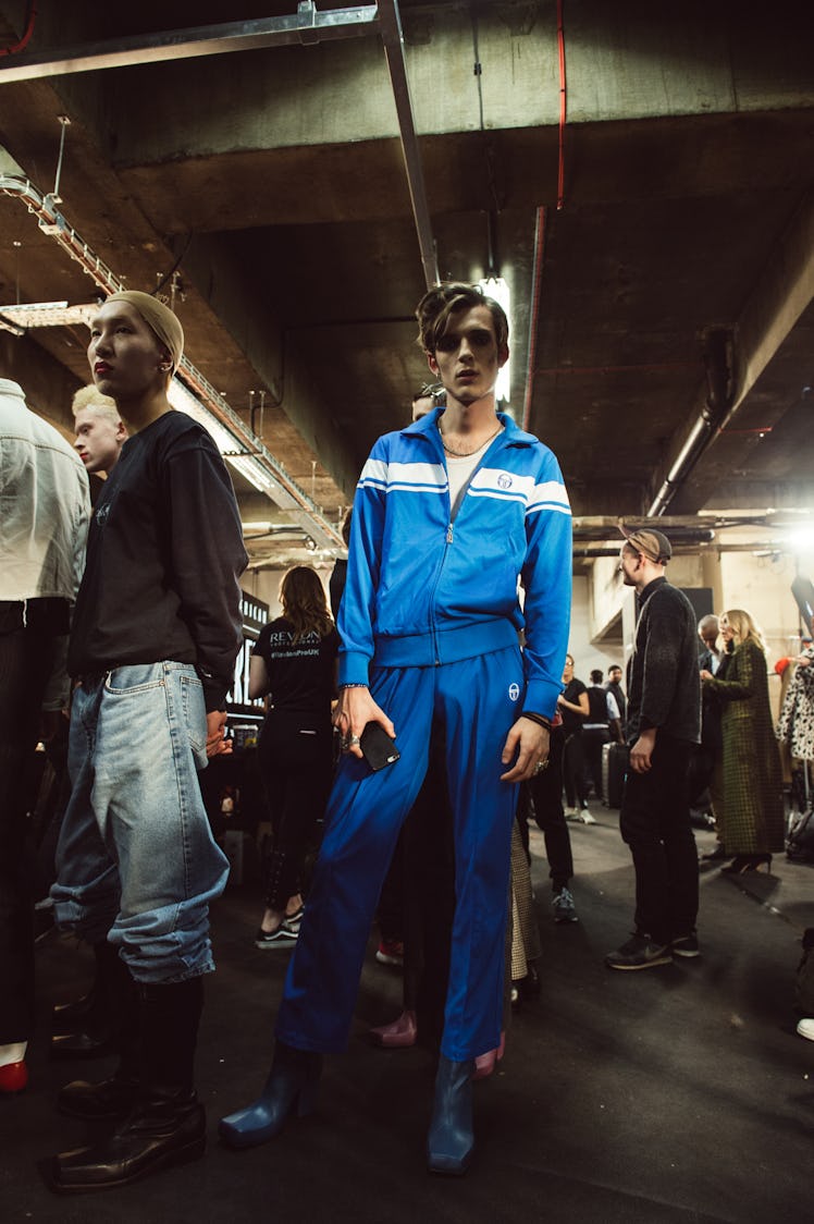 A male model posing in a blue tracksuit at Charles Jeffrey’s MAN Fall 2017 presentation