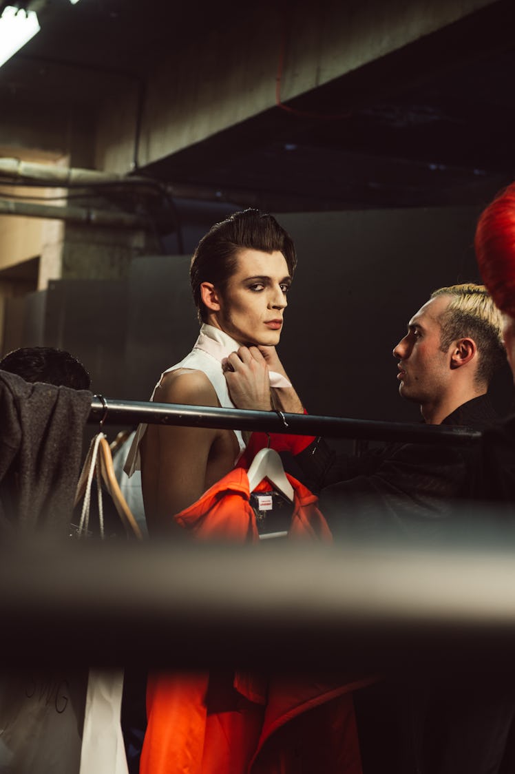 A stylist preparing a model that is wearing a white shirt for the Charles Jeffrey’s MAN Fall 2017 pr...