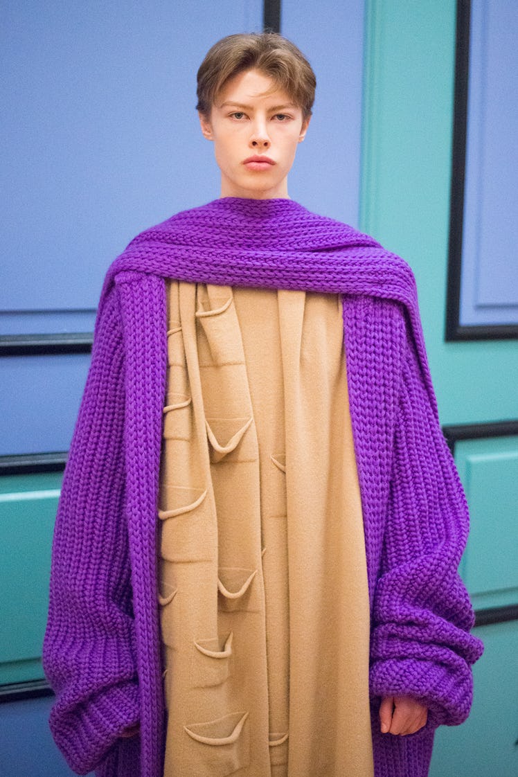 A model in a long beige dress and a purple knit coat from J.W. Anderson’s Fall/Winter 2017 Collectio...
