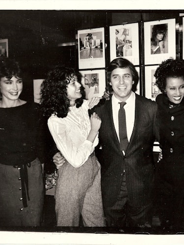 John Casablancas standing with supermodels in front of some of their photoshoots