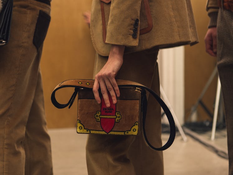 A close-up of a brown bag held backstage by a model at the Fall 2017 Prada Fashion Show