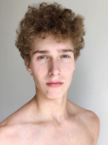 Male model, Mikolaj Kajak, with curly hair, shirtless while posing for a photo.