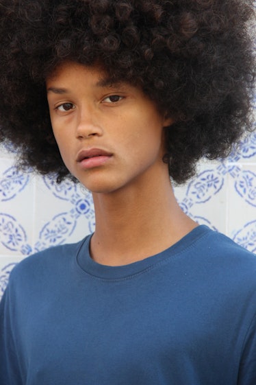 Male model, Joaquim Arnell, with his afro hair, wearing a blue t-shirt while posing for a photo.