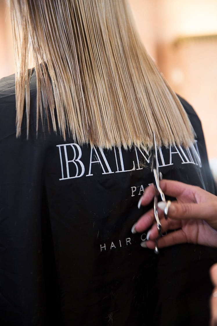 A model getting her hair trimmed backstage at Balmain Men’s 2017.