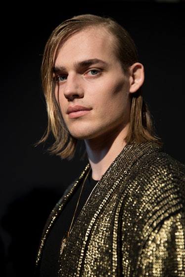 A male model posing in a golden sequin blazer from Balmain Men’s Fall 2017.