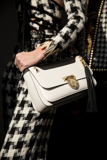 A model wearing Balmain Fall 2017 plaid dress and a white bag with golden details.