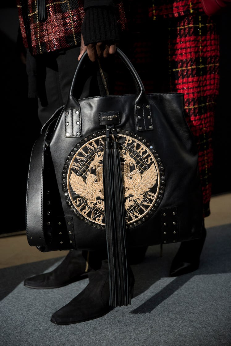 A model holding Balmain Fall 2017 black leather tote bag with embroidered logo.