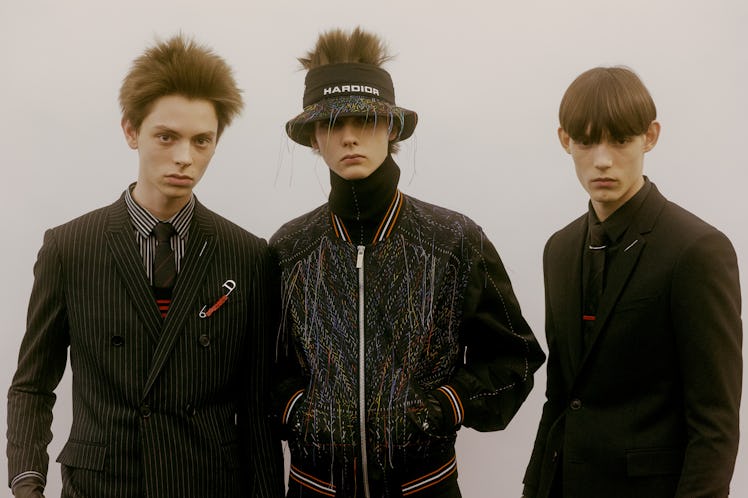 Three models posing in black suits and a bomber jacket by Dior