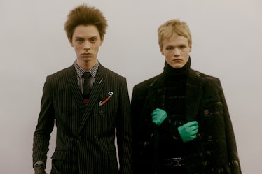 Two models backstage at the Dior Homme Fall 2017 show in a black suit and a black turtleneck with a ...