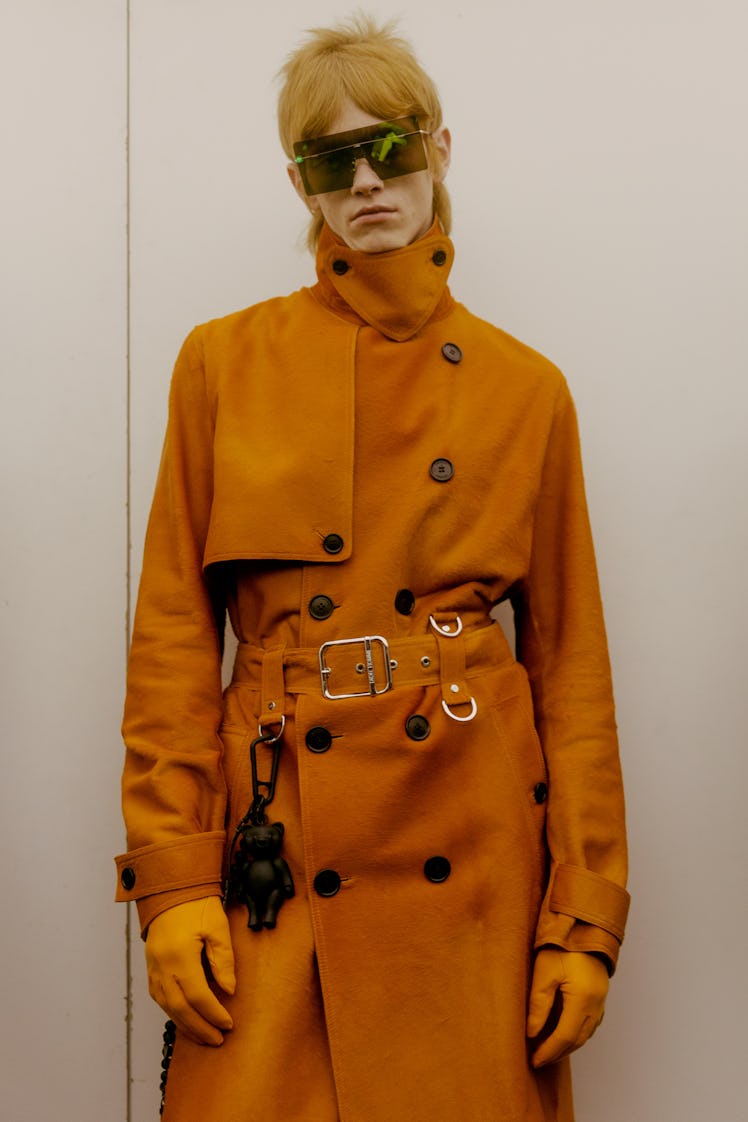 A model in a Dior trench coat in burnt orange and large squared sunglasses 