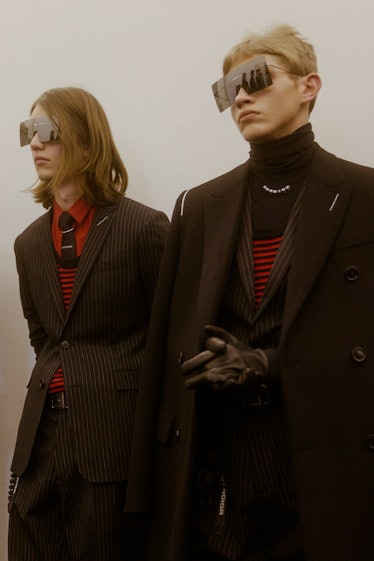 Two models in black Dior blazers and squared sunglasses posing backstage at the Fall 2017 show 