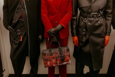 Three models at the Dior show in a red suit, black suit with a coat over it and in a black leather t...