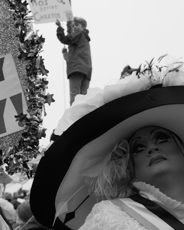 A drag queen in a large hat and a child slightly blurred in the background at the Women’s March in W...