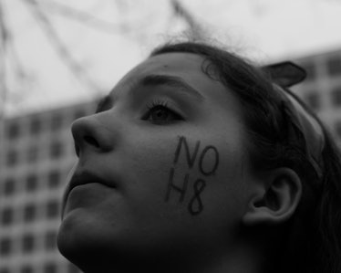 A young girl looking up with the words 'NO H8' written on her left cheek at the Women’s March in Was...