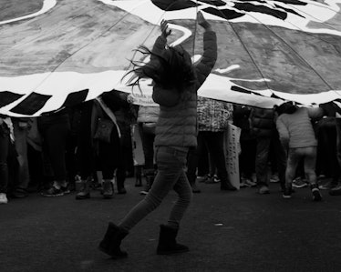 A young girl semi-jumping as she is walking and a group of people behind her  at the Women’s March i...