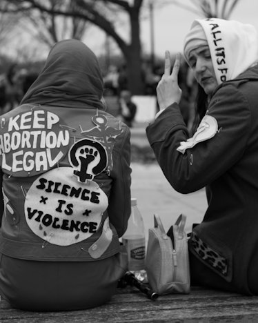 Two people sitting in jackets with protest symbols and slogans at the Women’s March in Washington D....