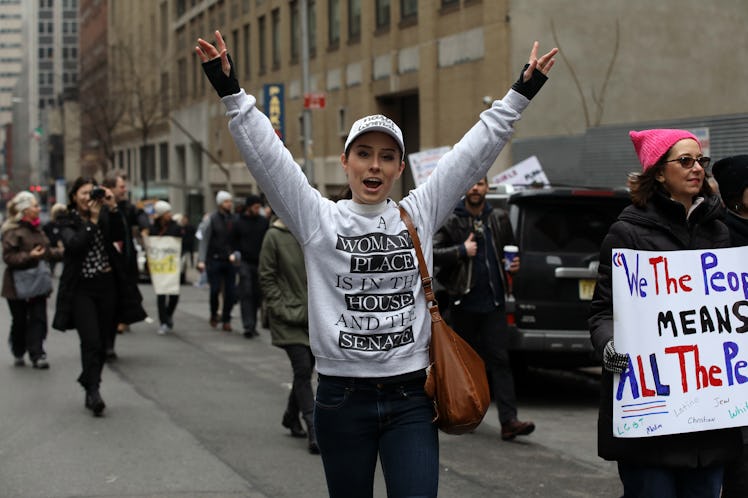 A woman with her arms raised and a text protest text print on her shirt at the New York City Women’s...