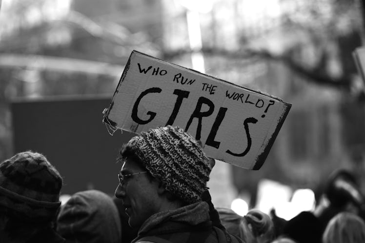 A man holding a poster 'Who run the world? GIRLS!' at the New York City Women's March