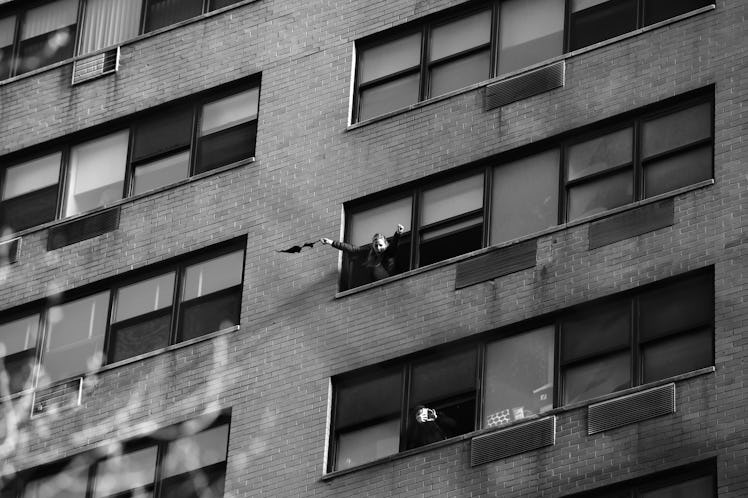 A woman waving from a window in a building at the New York City Women's March