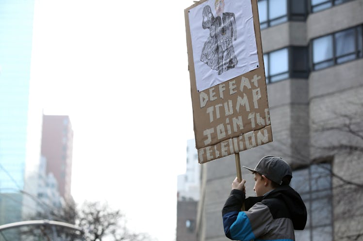 A boy holding the sign 'Defeat Trump join the rebellion' at the New York City Women's March