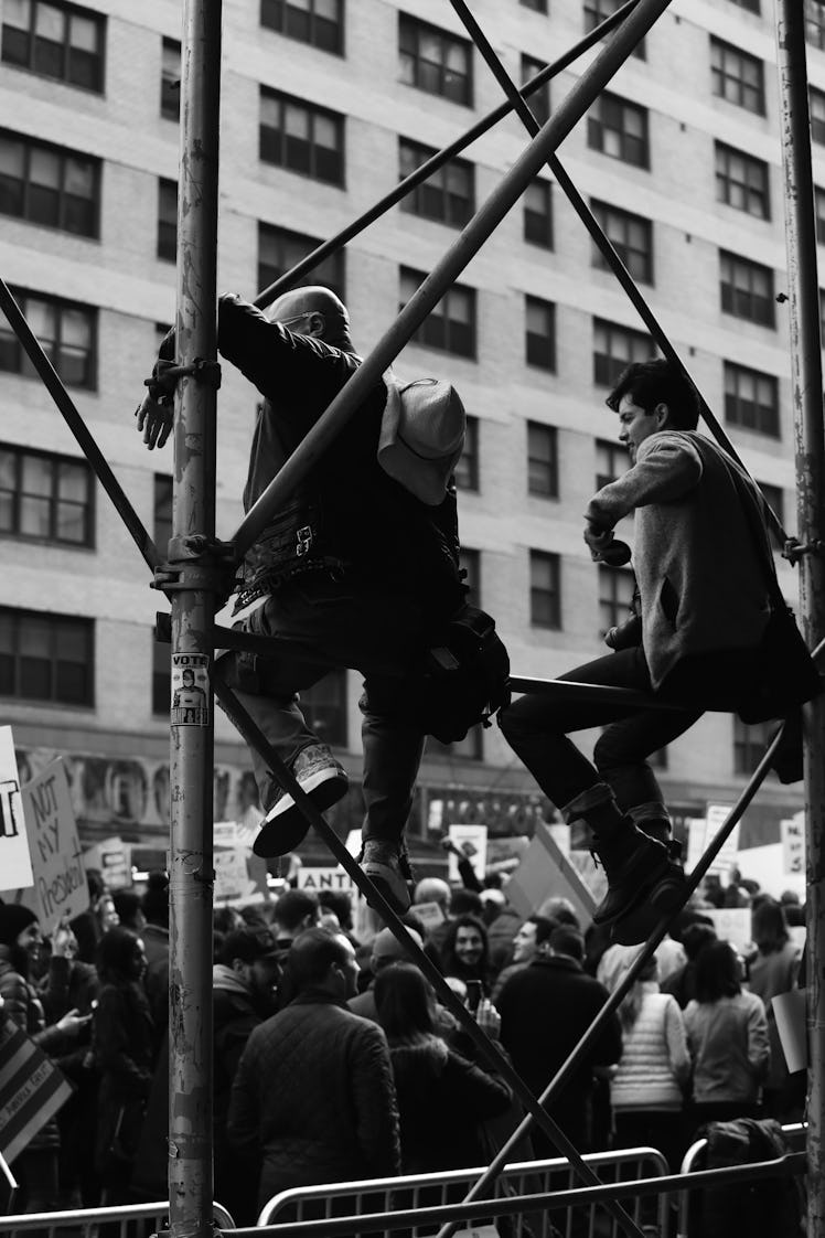 Two men climbing onto a building constructions at the New York City Women's March