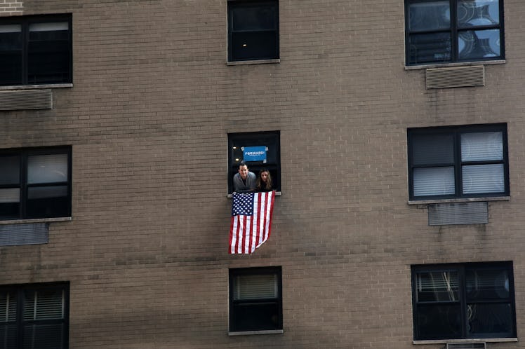 A man and a woman looking through a window in a holding the American Flag at the New York City Women...