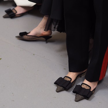 Models backstage wearing Dior heeled slippers with black bow.
