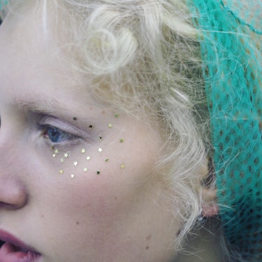 A close-up of a model wearing a mint green headscarf and stars eye stickers.