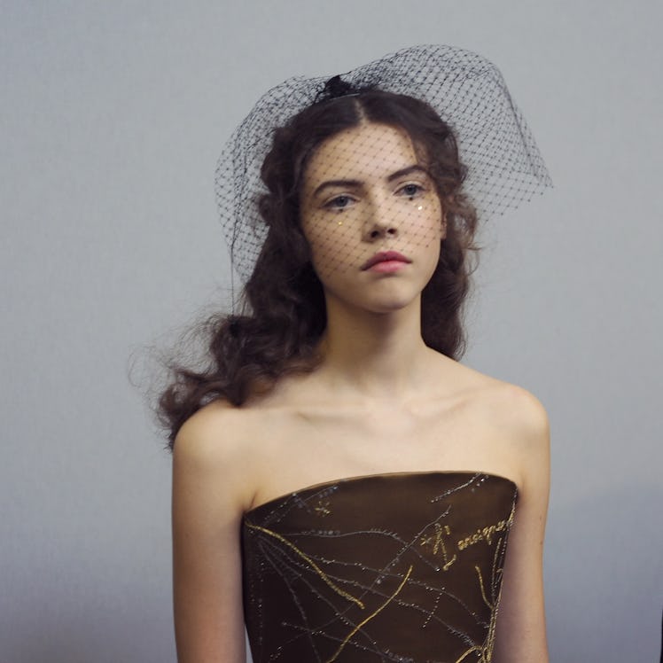 A model wearing a black mesh veil headpiece