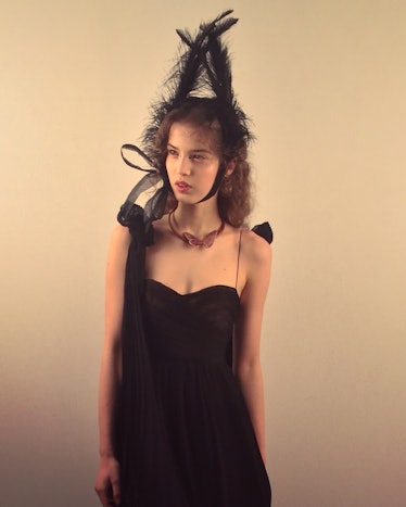 A model in a black dress and black feather headpiece 