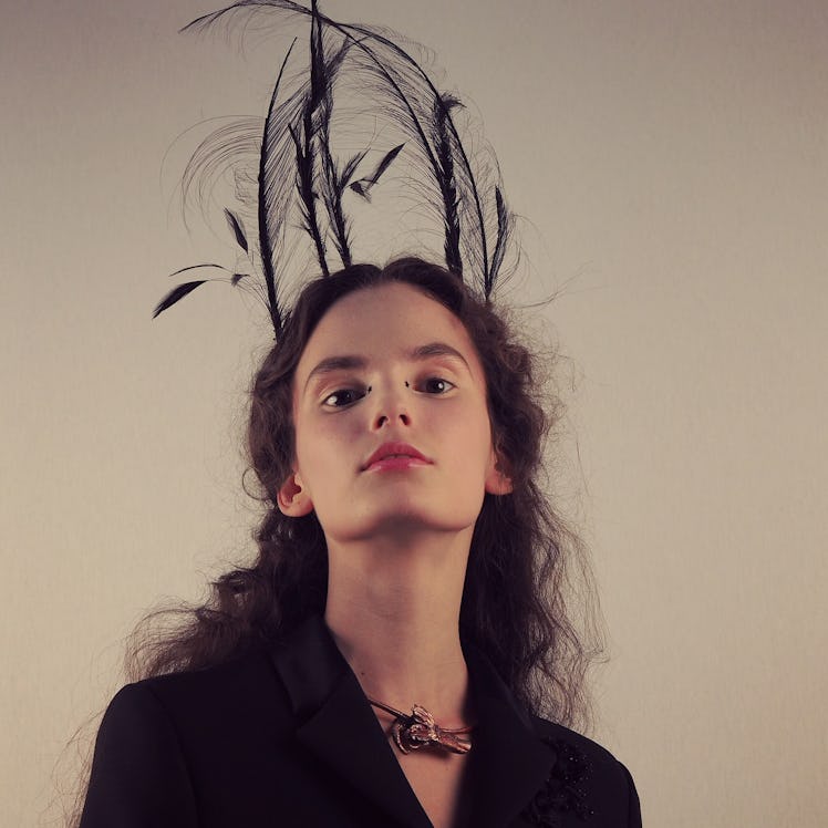 A model wearing Stephen Jones–designed headpiece with black feathers.