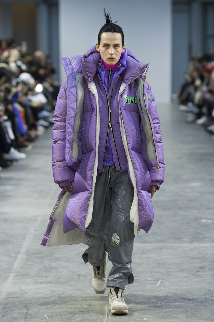 A model wearing gray pants and an oversized violet puffer jacket at the Sankuanz Fall 2017 runway