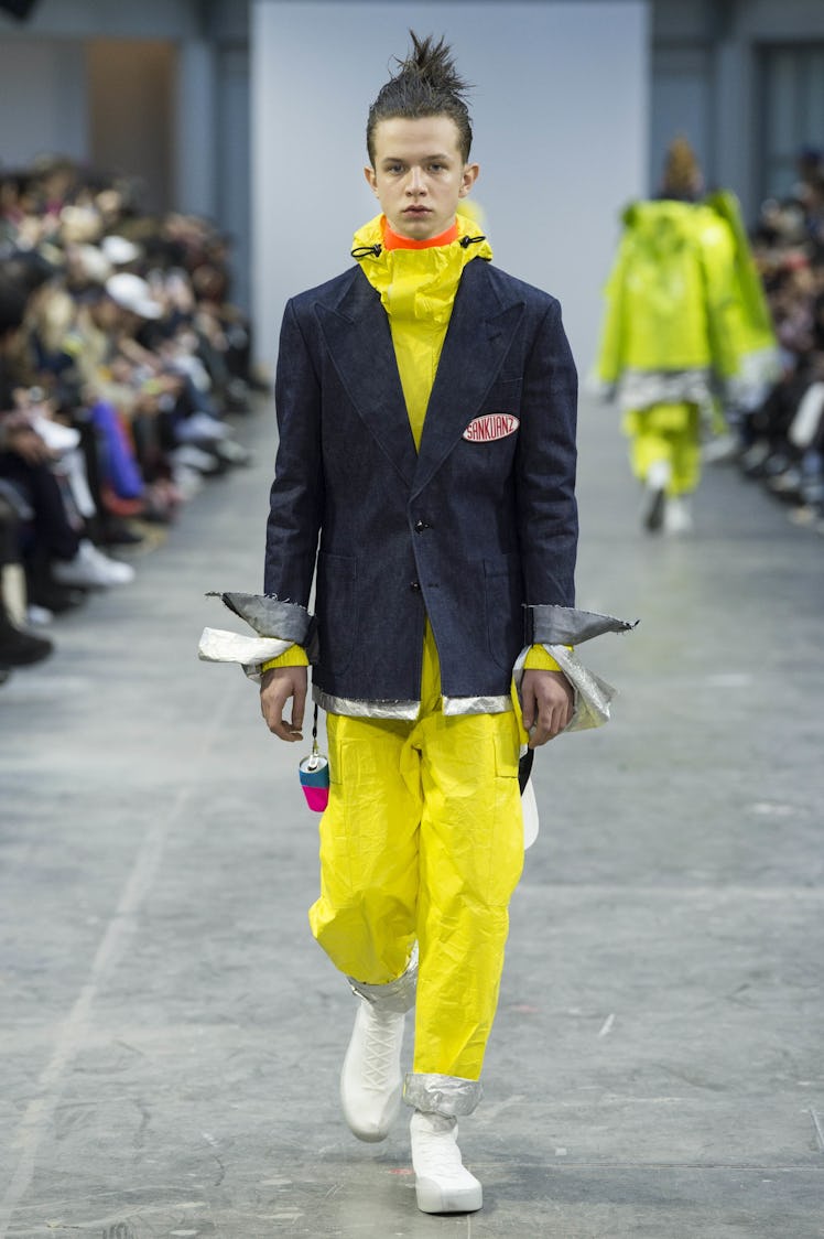 A model wearing a blazer with a yellow jumpsuit beneath at the Sankuanz Fall 2017 runway