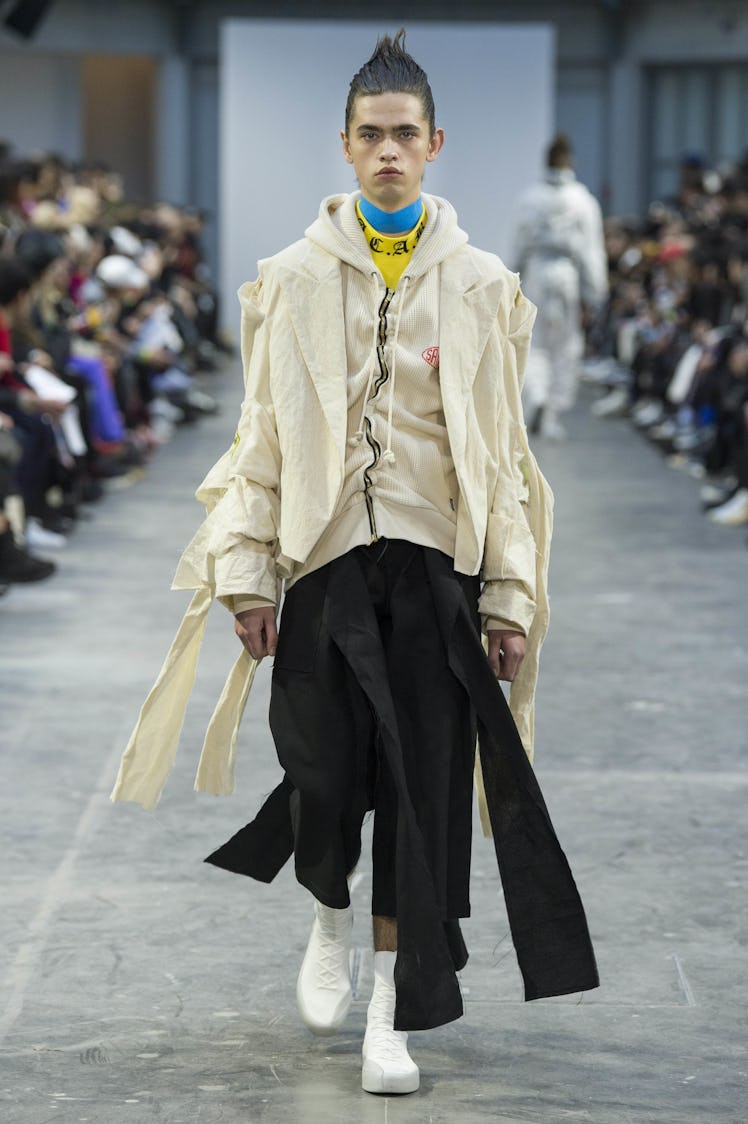 A model wearing black pants and a cream-colored hoodie and jacket at the Sankuanz Fall 2017 runway