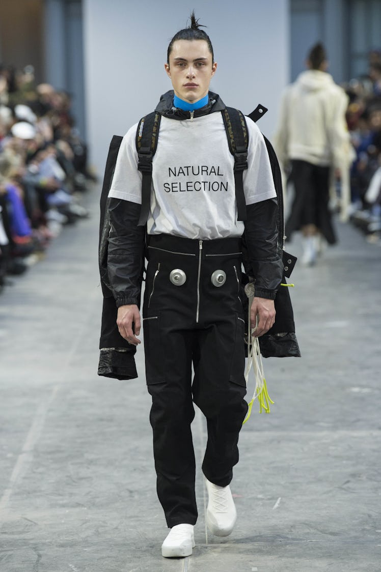 A model wearing black pants, a white shirt, and carrying a backpack at the Sankuanz Fall 2017 runway