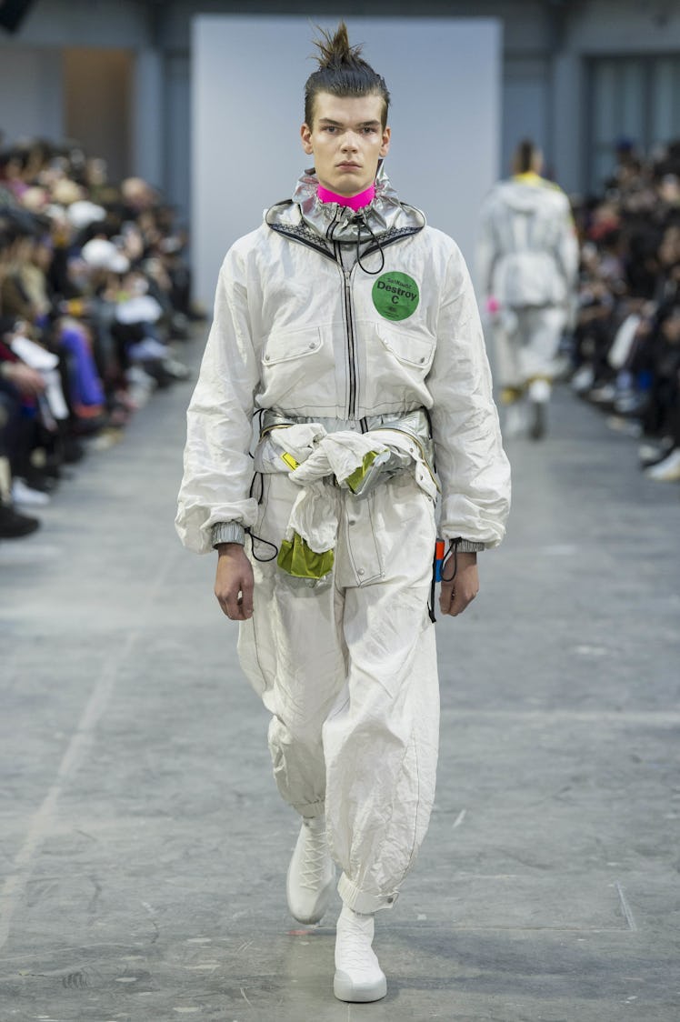 A model wearing a white jumpsuit with a jacket tied around waist at the Sankuanz Fall 2017 runway