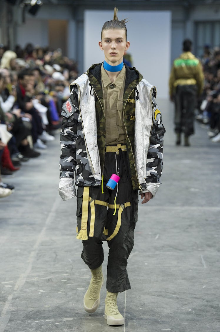 A model wearing black pants and a camo jacket with a blue choker at the Sankuanz Fall 2017 runway