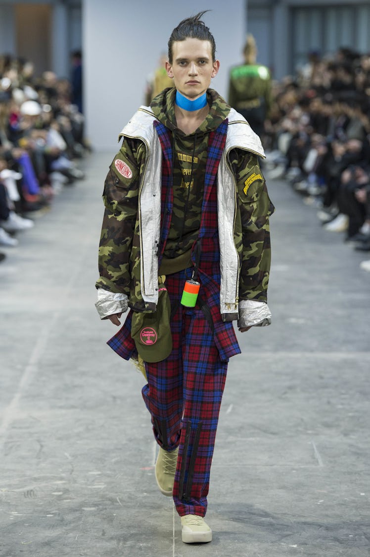 Model wearing a red and blue checkered outfit with a green camo jacket and a blue choker at the Sank...