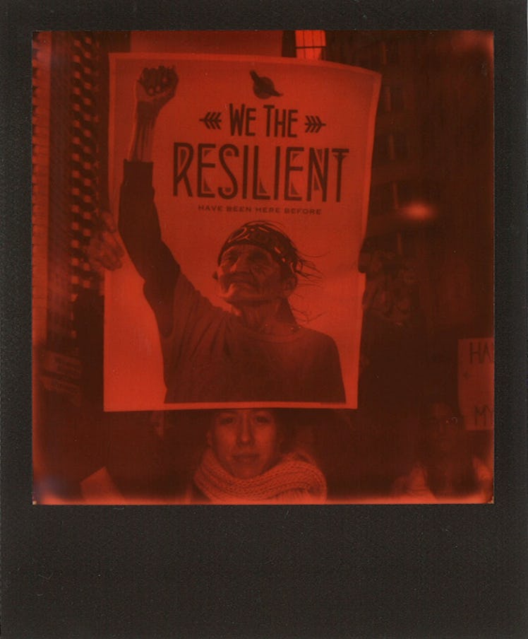 A woman holding a poster with "WE THE RESILIENT" text at the Women’s March in NYC