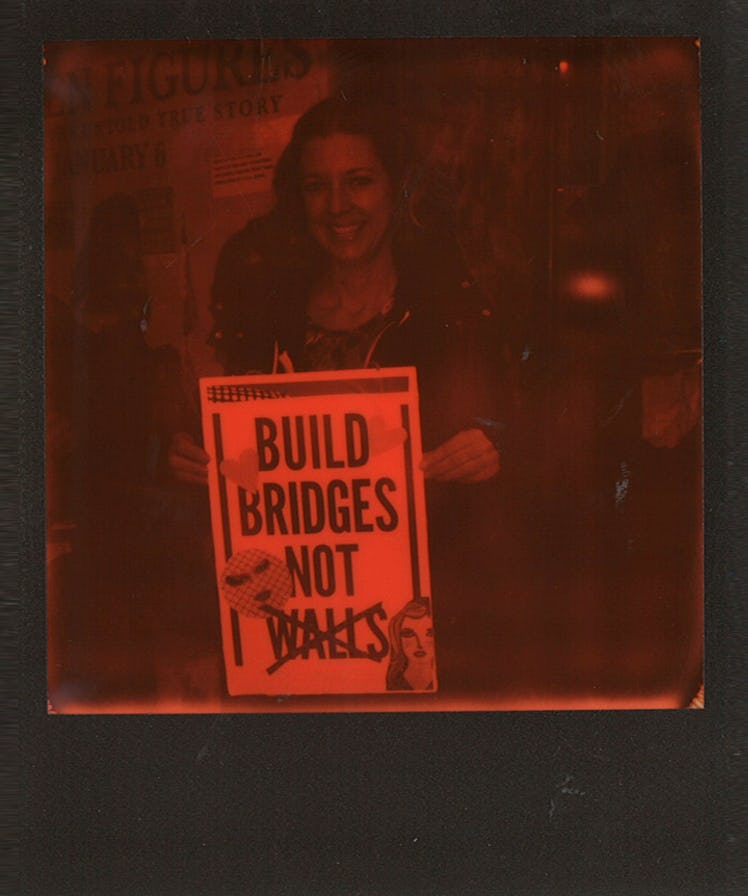 A woman holding a poster with "BUILD BRIDGES NOT WALLS" text at the Women’s March in NYC