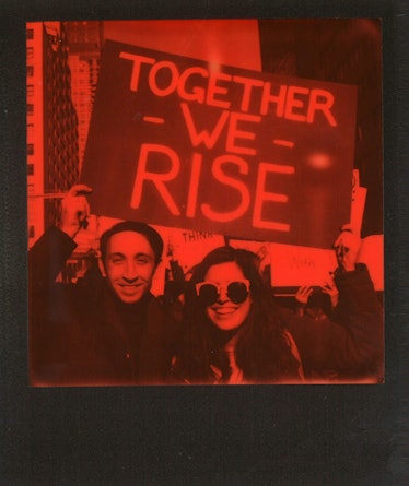 A man and a woman holding a poster with "TOGETHER WE RISE" text at the Women’s March in NYC