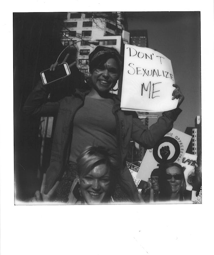 A woman holding a poster with "DON'T SEXUALIZE ME" text at the Women’s March in NYC